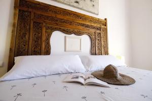 a bed with a book and a hat on it at La Casa de la Luz. ArtistHome in Almodóvar del Río +34 photos