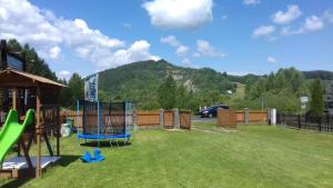 a playground in a yard with a mountain in the background at Domki pod Żukowcem in Solina