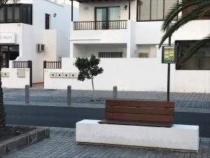 un banc sur un trottoir devant un bâtiment dans l'établissement LC Apartamento Playa Honda, à Playa Honda