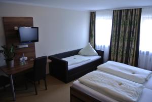 a hotel room with a couch and a table and a tv at Hotel Daimerwirt in Moosinning