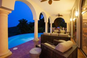 a patio with a pool and chairs and a ceiling fan at La Colina - 2 Bedrooms in West Bay