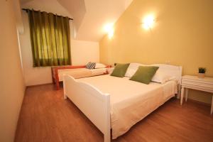 una camera da letto con un grande letto bianco con cuscini verdi di Apartmani Kristijan a Jesenice