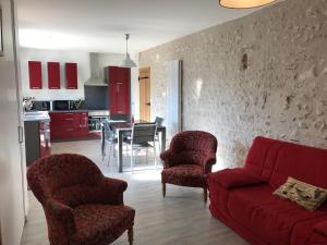 uma sala de estar com um sofá vermelho, cadeiras e uma mesa em Gîte du Parc des Mauves em Meung-sur-Loire