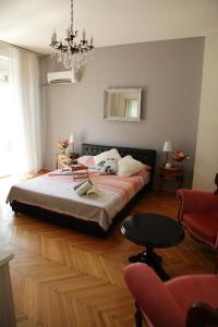 um quarto com uma cama, uma mesa e um lustre em London Apartment em Belgrado