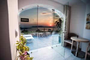 Cette chambre dispose d'une porte en verre offrant une vue sur le coucher du soleil. dans l'établissement Kratiras View Luxury Suites, à Fira