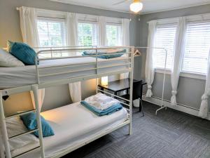 a bunk bed room with two bunk beds and two windows at The Wayfaring Buckeye Hostel in Columbus