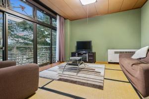 a living room with a couch and a tv at White Horse Hotel in Hakuba