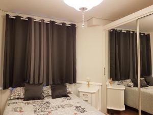 a bedroom with black curtains and a bed and a mirror at Apartamento Homeland 305 in Gramado