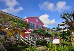 墾丁的住宿－墾丁夏都沙灘酒店，粉红色和黄色的建筑,前面有标志