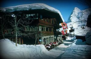 a building covered in snow in front of a mountain at Hotel Blumental in Mürren