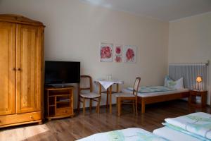 ein Wohnzimmer mit einem TV und einem Tisch mit Stühlen in der Unterkunft Gästehaus Mariola in Wulkaprodersdorf