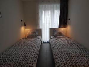 ディスフクにある'APPARTEMENT RANDDUIN' Bed by the Seaのベッド2台(照明付)が備わる客室です。