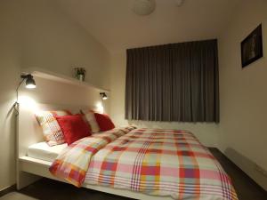 Un dormitorio con una cama con almohadas rojas y una ventana en 'APPARTEMENT RANDDUIN' Bed by the Sea, en Dishoek