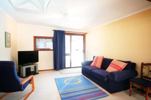 a living room with a blue couch and a tv at Deni Golf Resort in Deniliquin