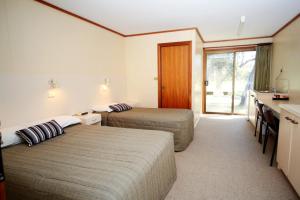 a hotel room with two beds and a kitchen and a sink at Deni Golf Resort in Deniliquin