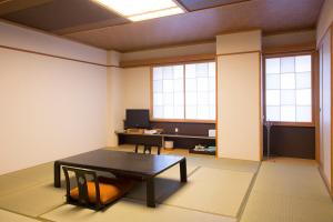 a room with a table and a desk and two windows at Wakkanai Grand Hotel in Wakkanai