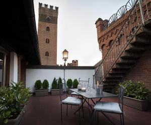 un patio con tavolo, sedie e torre dell'orologio. di Castello Medici del Vascello ad Asti