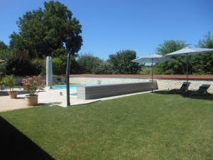 a pool with a bench and two chairs and an umbrella at le gîte de viré in Viré