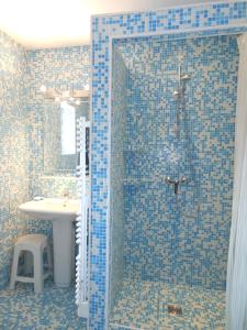 La salle de bains est pourvue de carrelage bleu, d'une douche et d'un lavabo. dans l'établissement le gîte de viré, à Viré