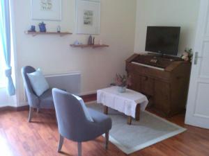 a living room with a television and two chairs and a table at L'AURE BLEUE in Bayeux