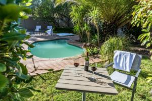 a picnic table with a bottle of wine next to a pool at Le Petit Chateau Guest House in Durbanville