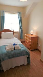 a bedroom with a bed and a dresser and a window at Saint Patrick's Cottages (Downpatrick) in Downpatrick