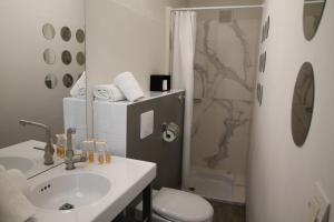 a bathroom with a toilet, sink, mirror and bathtub at Régina Boutique Hotel in Avignon