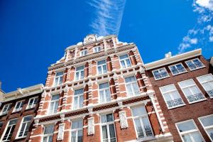 a red brick building with white windows and a blue sky at Hotel Nes in Amsterdam
