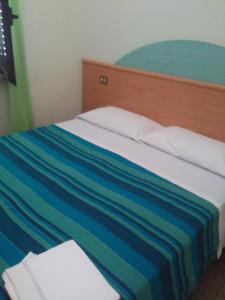 a bed with a colorful striped blanket on it at Regina di cuori in LʼAquila