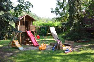 a backyard with a playground with a house and swings at Hotel Zakątek Leśny in Cierpice