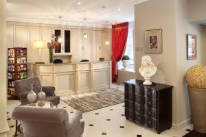 uma sala de estar com um sofá e uma cadeira em Hôtel des Comédies em Paris