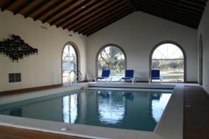 a large swimming pool in a house with chairs at Monte das Faias Cork Farm Hotel in Grândola