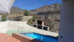 a swimming pool in front of a stone building at Casa Rural de Perera in San Bartolomé