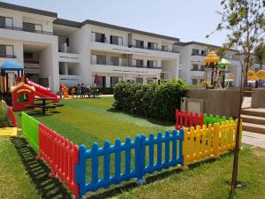a playground with a colorful fence in front of a building at Marbella Beach Residency in Mansouria