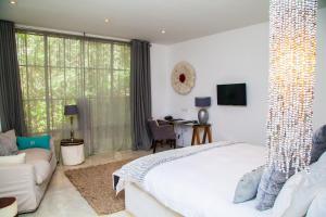 a bedroom with a large white bed and a couch at Latitude 15 Degrees in Lusaka