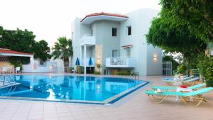 a large swimming pool with a patio area with chairs and umbrellas at Melissa Apartments in Malia