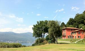 czerwony dom na szczycie wzgórza z drzewem w obiekcie Locanda Pozzetto w mieście Laveno-Mombello