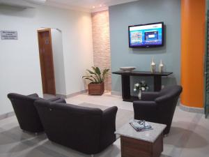 a waiting room with chairs and a tv on a wall at Lord Hotel Camburi in Vitória