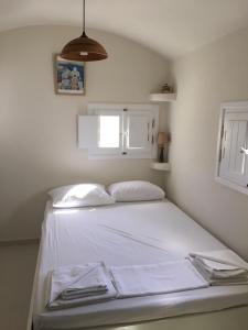 a white bed in a room with a window at Cosy studio in Santorini in Éxo Goniá