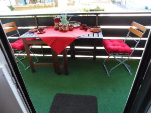 a table with a red table cloth and chairs on a balcony at Schnuckelig und Fein in Oberstaufen