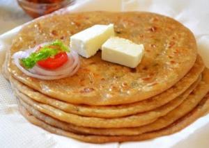 a stack of pancakes with cheese and tomatoes on top at Hotel Krishnas in Amritsar