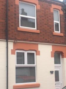 uma casa branca com três janelas e um edifício de tijolos em Townhouse @Richmond Street Stoke em Stoke-on-Trent