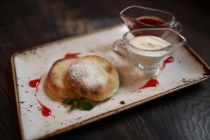 a plate with two rolls and a cup of sauce at Tchaikovsky Hotel in Moscow