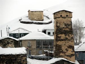ein alter Turm im Schnee neben einem Berg in der Unterkunft Guesthouse Marshan in Uschguli
