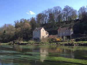 two houses on a hill next to a river at Le Moulin de Cors in Oulches