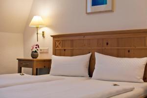 a bedroom with two beds with white pillows and a table at Hotel Gruenshof in Walldorf