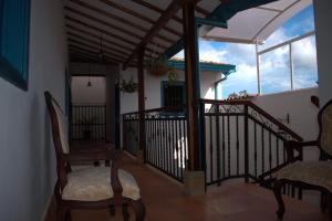 a balcony with two rocking chairs and a house at Hotel Casa Oasis in Zapatoca