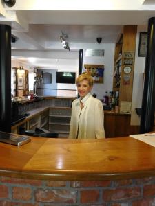 Una donna in piedi dietro un bancone in una cucina di The Railway Inn a Forden