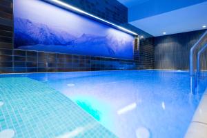 a swimming pool with a large screen on the wall at Hotel Angela in Lech am Arlberg