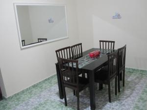 mesa de comedor negra con sillas y espejo en Al-Kahfi Homestay en Dungun